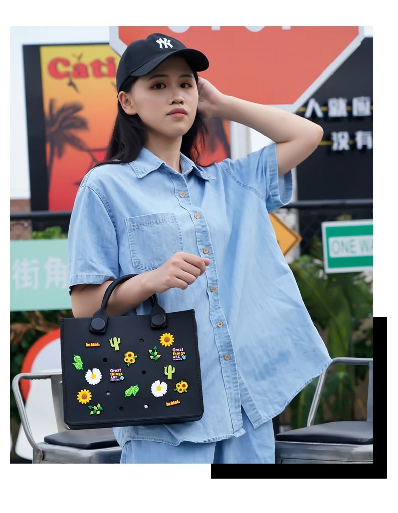 Ragazza vestita di jeans con cappellino nero e borsa in gomma eva nera con charms colorati di fiori e cactus e girasoli